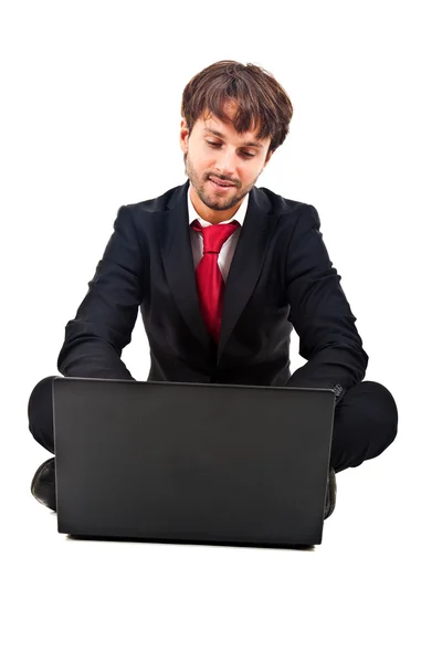 Young businessman sitting on the floor in front of his laptop — Stock Photo, Image