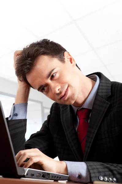 Um retrato de um jovem homem de negócios bonito sendo atencioso olhando para seu laptop — Fotografia de Stock