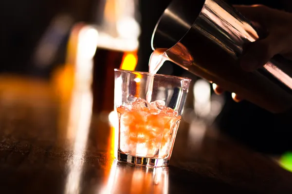 Barman pouring a cocktail into a glass — Stock Photo, Image