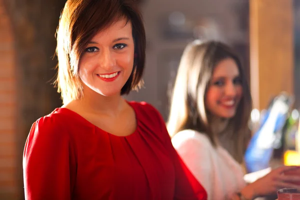 Two young women enjoying a drink in a pub — Stock Photo, Image