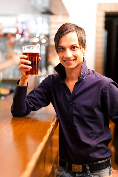 Молодой человек пьет пиво в пабе — стоковое фото