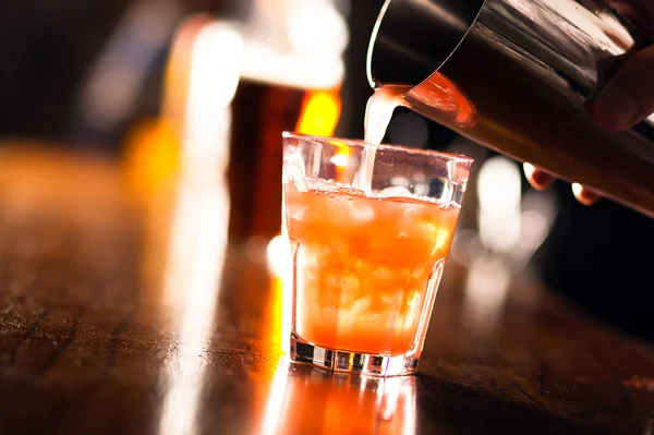 Barman pouring a cocktail into a glass — Stock Photo, Image