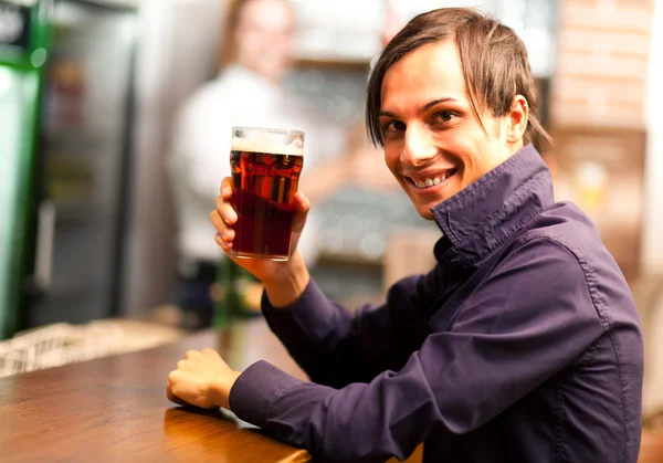 Jeune homme prenant une bière dans un pub — Photo