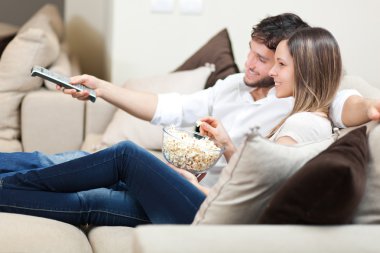 Young couple watching tv on a sofa clipart