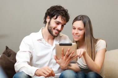 mutlu çift kanepede bir tablet