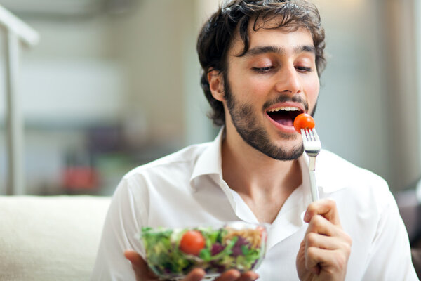 Молодой человек ест здоровый салат
