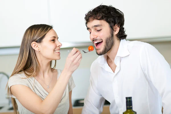 Woman feeding his husband with a tomato — Stock Photo, Image