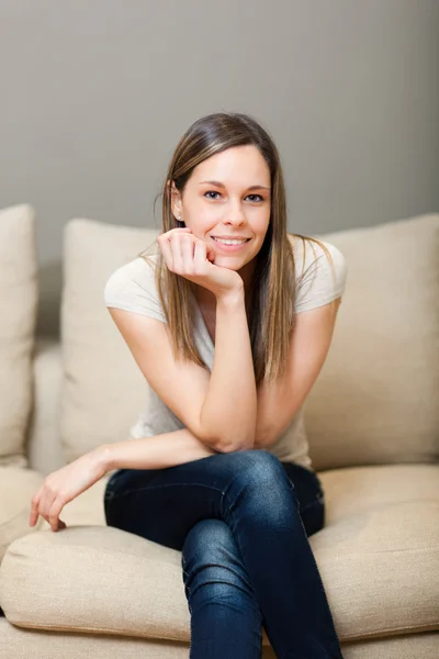 Młoda kobieta siedząca na kanapie — Zdjęcie stockowe