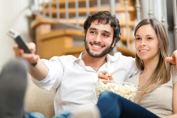 Junges Paar vor dem Fernseher auf einem Sofa — Stockfoto