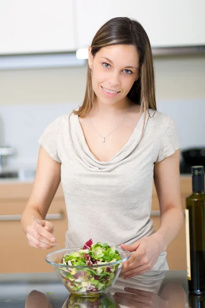 Porträtt av en leende kvinna som krydda en sallad — Stockfoto