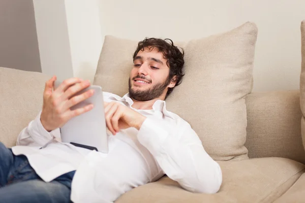 Man met een Tablet PC op een bank — Stockfoto