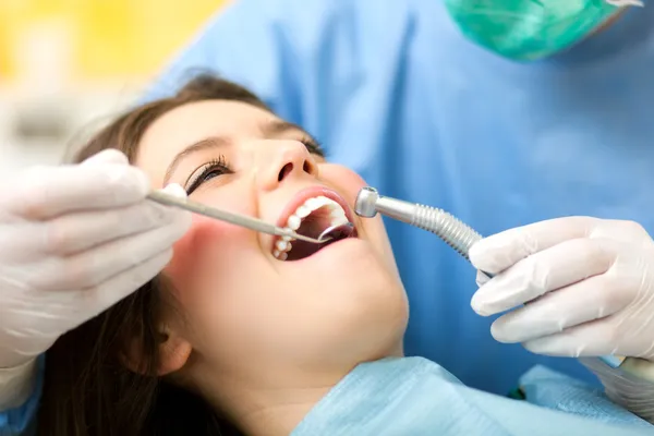 Dentista cura una paziente donna — Foto Stock