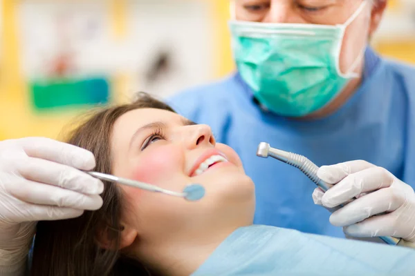 Dentista fazendo um tratamento odontológico em uma paciente do sexo feminino — Fotografia de Stock