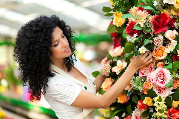 Vackra kvinnliga florist röra några blommor i ett växthus — Stockfoto