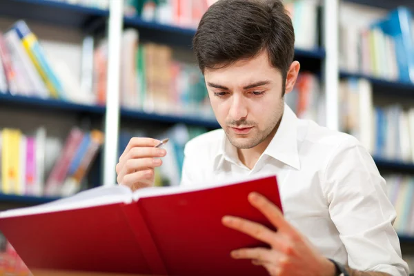 Killen läser en bok i ett bibliotek — Stockfoto