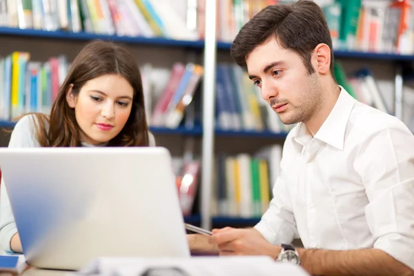 Estudantes usando seu laptop em uma biblioteca — Fotografia de Stock