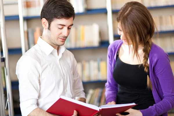 Amis lisant un livre dans une bibliothèque — Photo