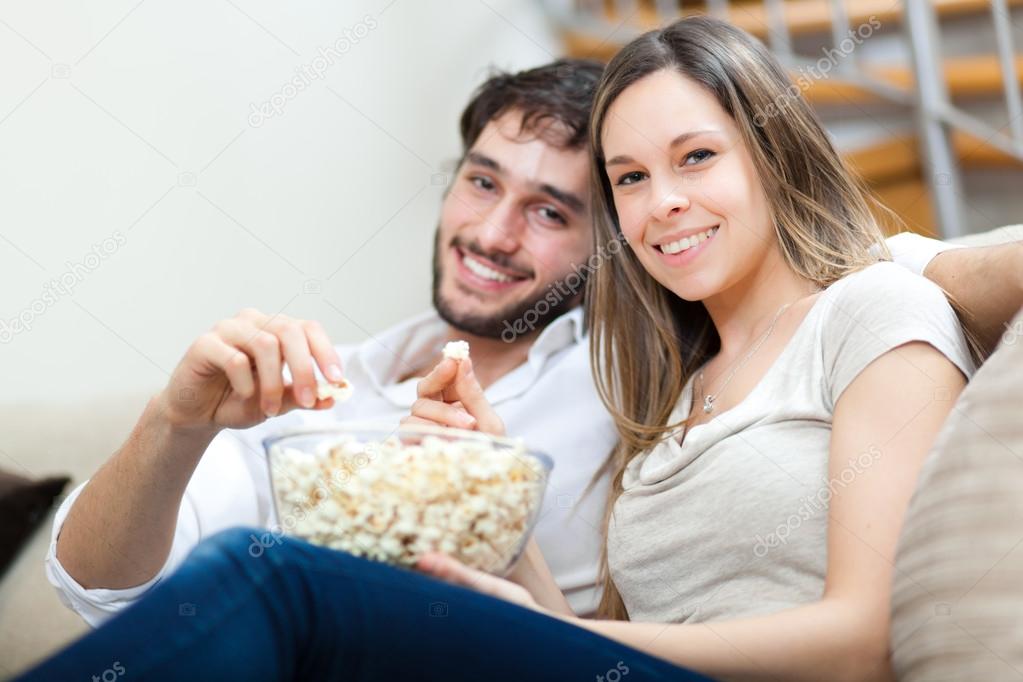 Couple eating popcorn while watching a movie