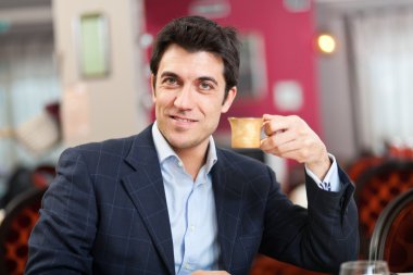 kahve içme bir restoranda bir masada oturan genç adam gülümsüyor