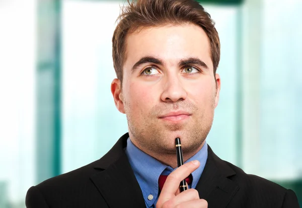 Задумчивый бизнесмен держит ручку на подбородке — стоковое фото