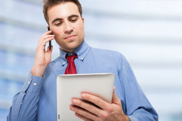 Человек разговаривает по телефону во время использования планшета — стоковое фото