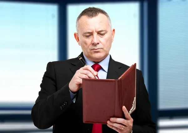 Homem de negócios maduro escrevendo em sua agenda — Fotografia de Stock