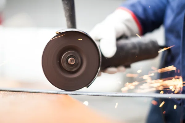 Trabalhador usando um moedor em uma placa de metal — Fotografia de Stock