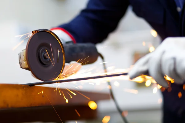 Werknemer met behulp van een molen op een metalen plaat — Stockfoto