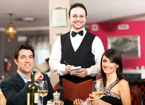 Gelukkige paar en ober glimlachend in het restaurant — Stockfoto