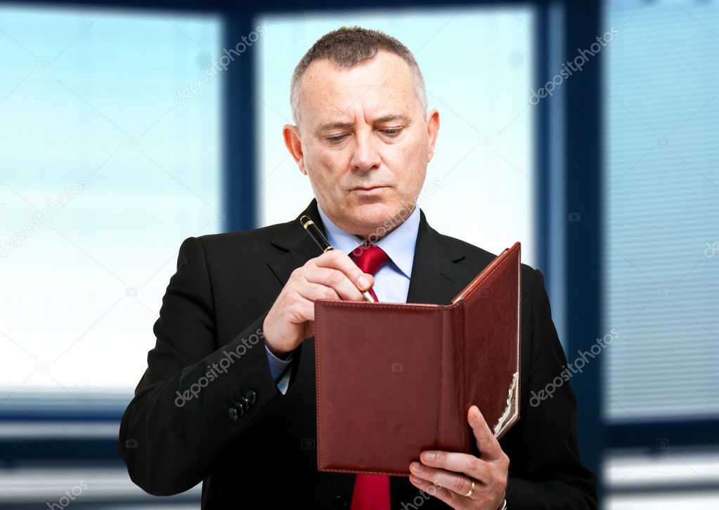Mature businessman writing on his agenda