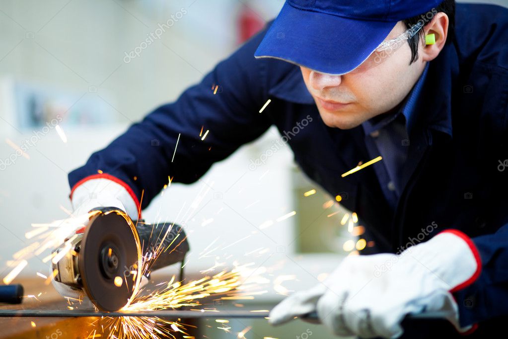 Worker using a grinder on a metal plate