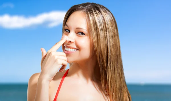 Femme appliquant de la crème solaire sur son nez — Photo