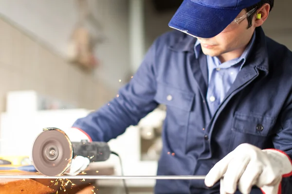 Lavoratore che macina una piastra metallica — Foto Stock