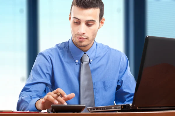 Portret van een jonge knappe zakenman op zijn laptop — Stockfoto