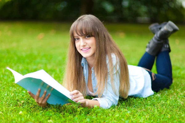 Mujer estudiante acostada en la hierba — Foto de Stock