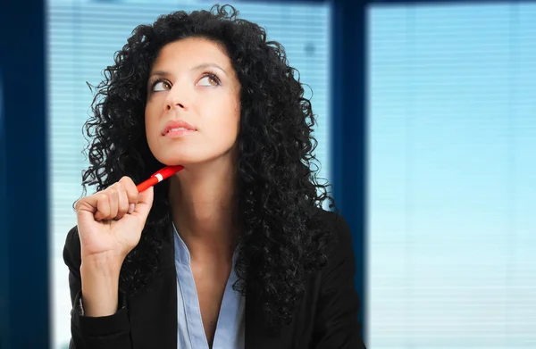 Mujer de negocios pensativa sosteniendo una pluma cerca de su boca —  Fotos de Stock