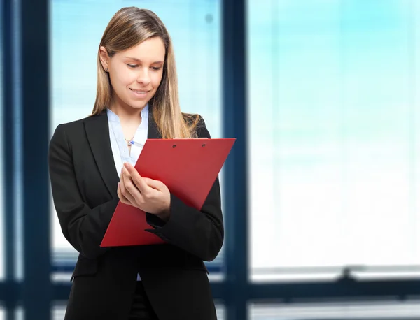 Femme d'affaires écrit sur un presse-papiers dans un bureau — Photo