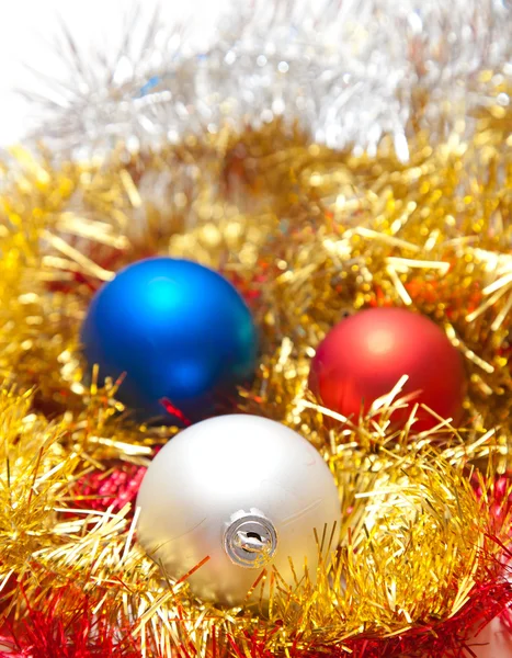 Tre julgranskulor liggande på några dekorationer — Stockfoto