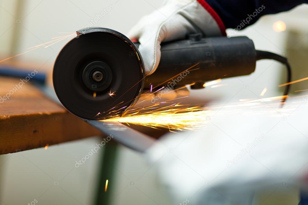 Worker grinding a metal bar