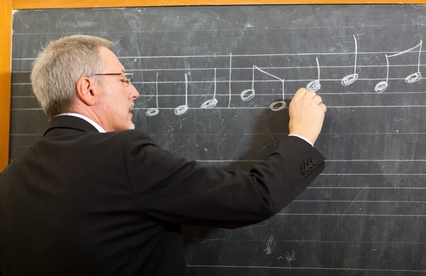 Teacher writing note on blackboard — Stock Photo, Image