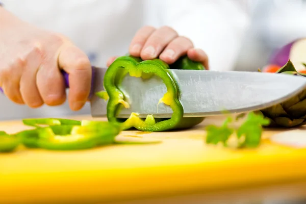 Chef cutting a green pepper — Stock Photo, Image