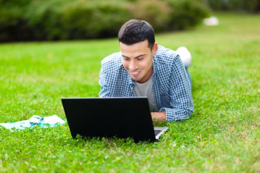 çimenlerin üzerinde kendi dizüstü kullanan adam