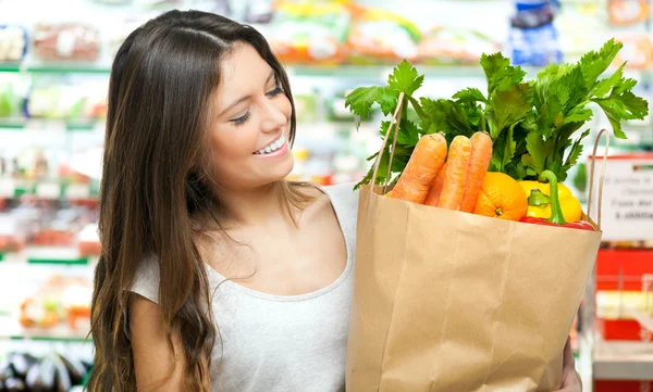 Mujer sosteniendo una bolsa llena de verduras —  Fotos de Stock