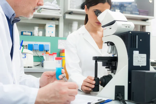 Vrouw met behulp van een microscoop in een laboratorium — Stockfoto
