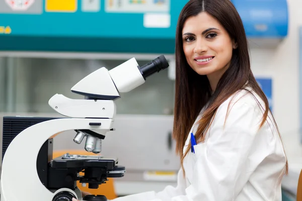 Mulher usando um microscópio em um laboratório — Fotografia de Stock