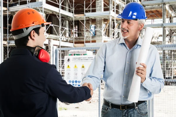 Workers shaking hands in a construction site — Stock Photo, Image