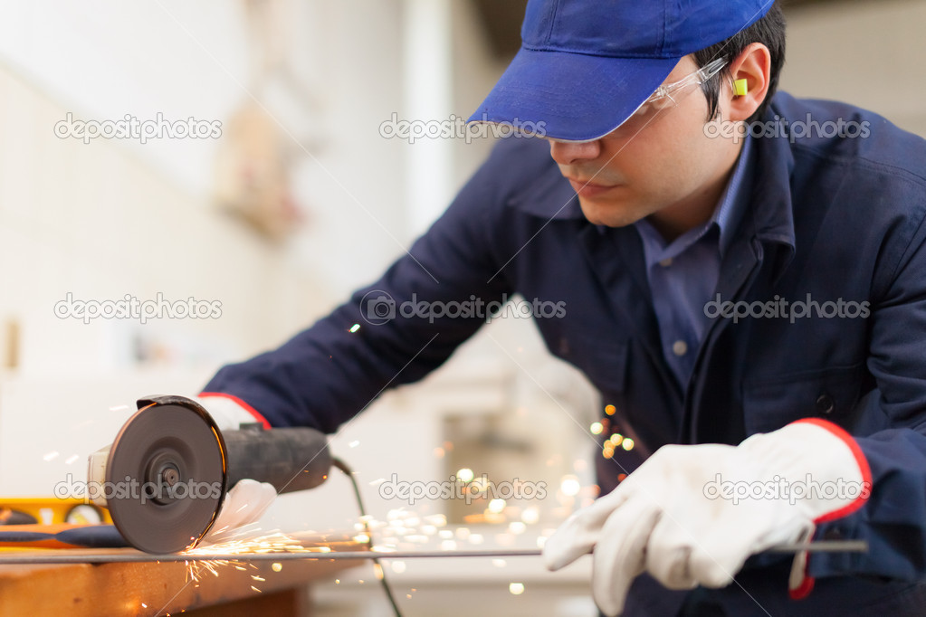 Worker using a grinder in a factory