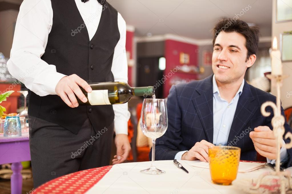 Waiter serving wine to man