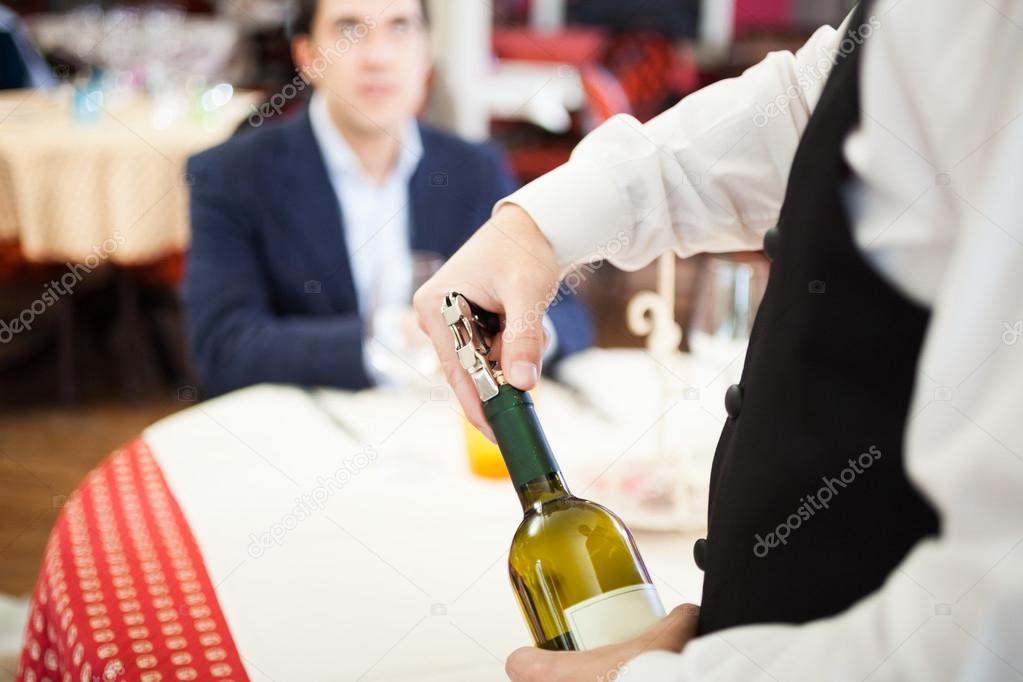 Waiter uncorking wine bottle