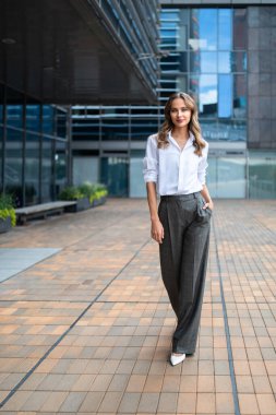 Modern bir şehir meydanında yürüyen iş kadını